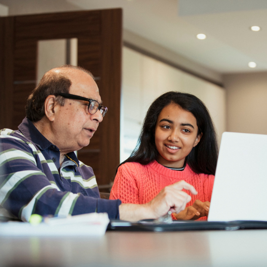 Teen Tech Tutors - Teen girl assists senior man on a computer notebook